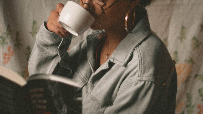 A person enjoys a cup of coffee while reading a book.